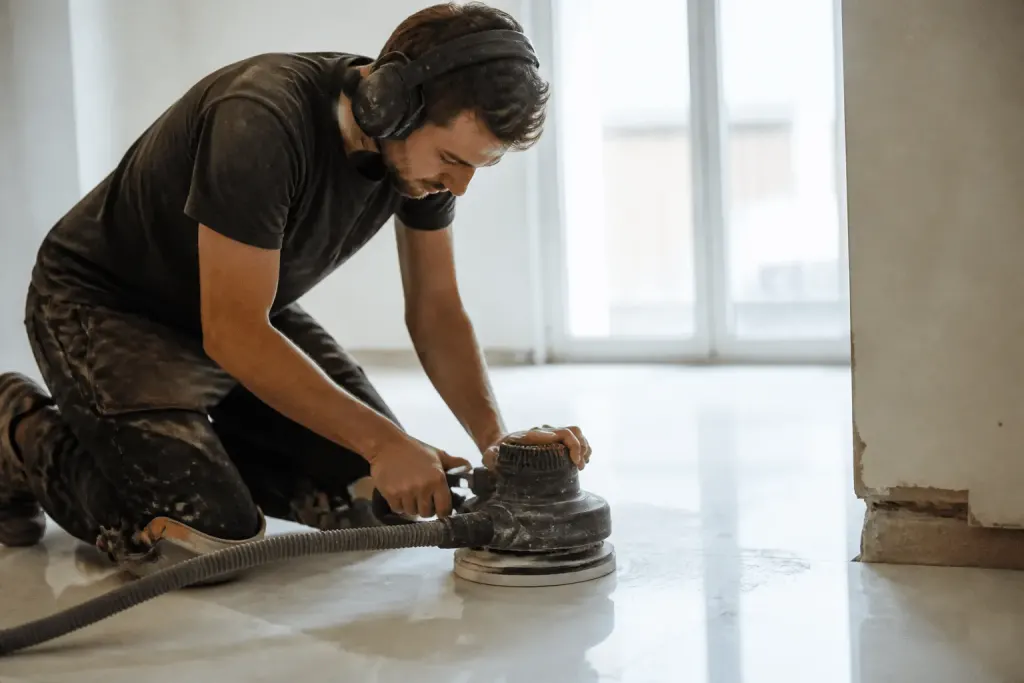 Carreleur professionnel ponçant surface blanche avec machine spécialisée