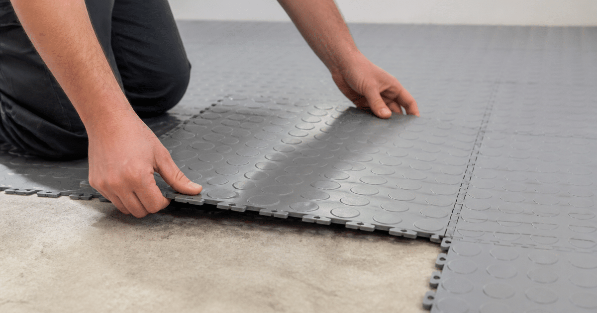 Mains assemblant des carreaux plastique clipsables sur sol