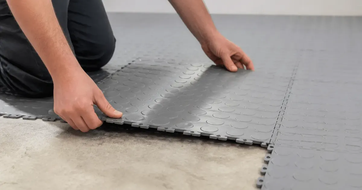 Mains assemblant des carreaux plastique clipsables sur sol