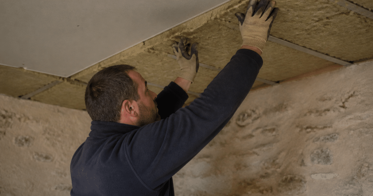 Ouvrier appliquant isolant thermique sous plafond existant