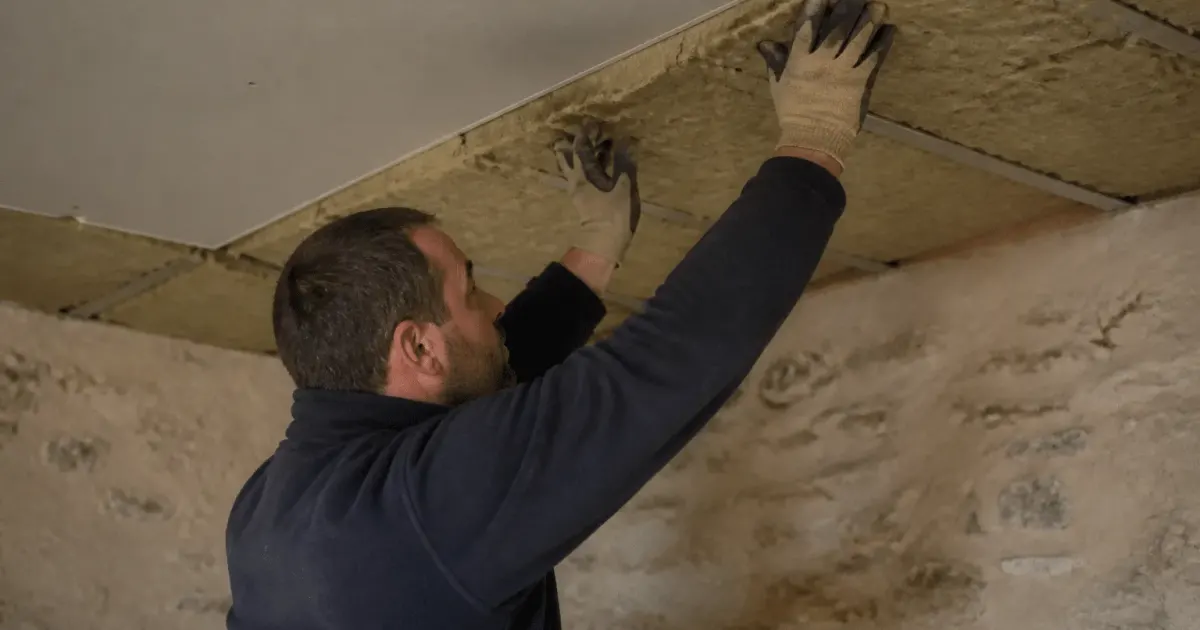 Ouvrier appliquant isolant thermique sous plafond existant