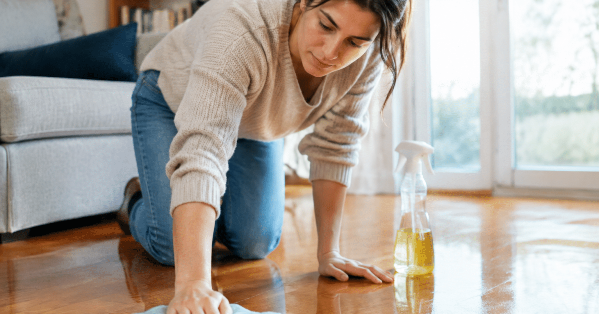 Personne agenouille appliquant produit sur parquet brillant avec chiffon
