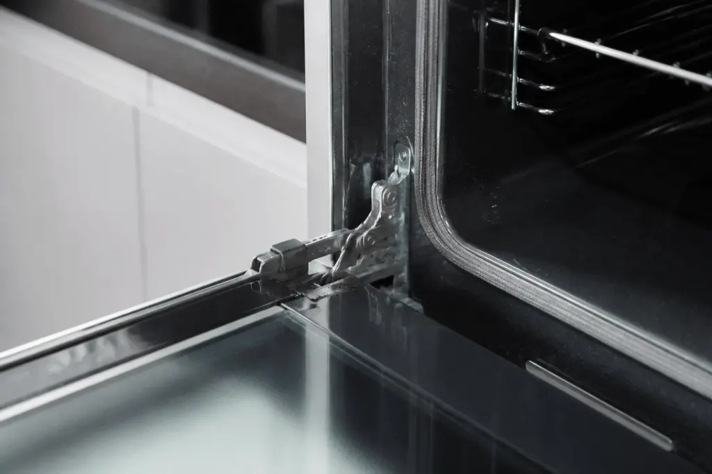Porte four ouverte avec clips visibles sur charnières