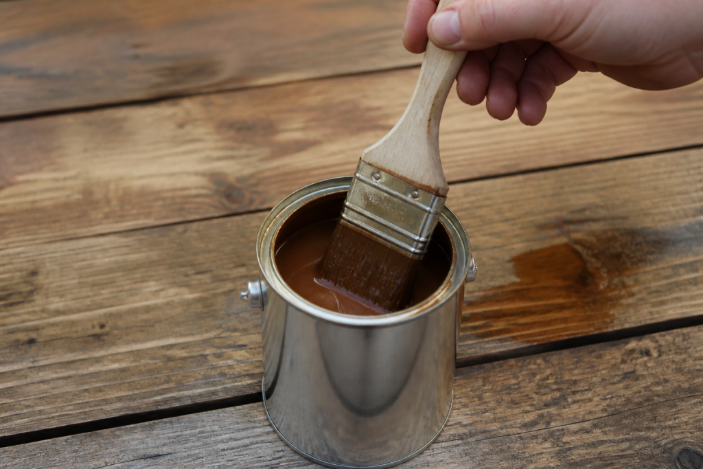 Pinceau trempe dans pot peinture brillante sur bois