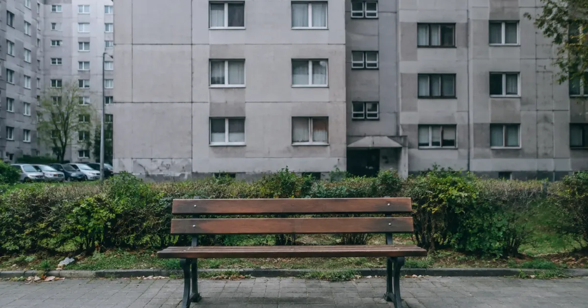 Banc vide en bois devant un grand immeuble gris