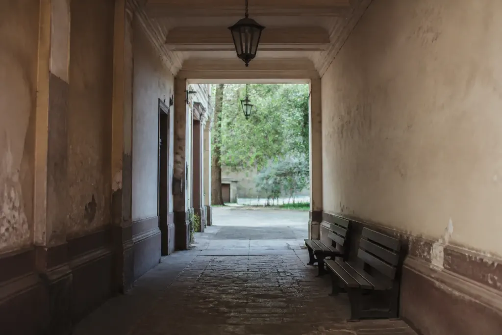 Hall immeuble abime, lampadaire eteint, bancs vides
