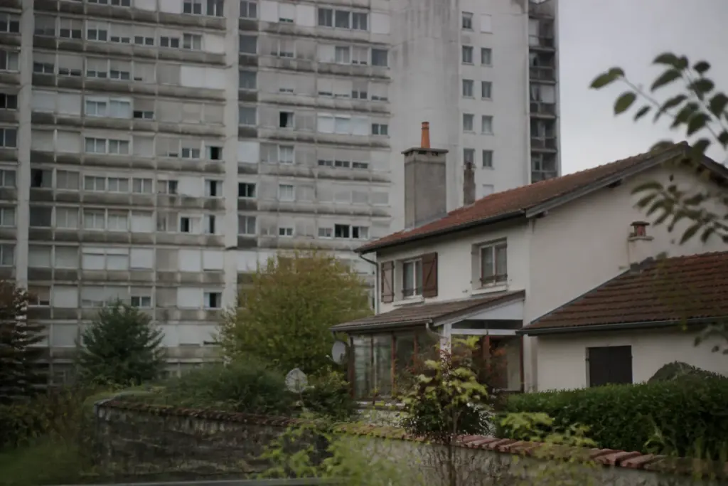 Immeubles gris vieillissants face a des pavillons avec jardins