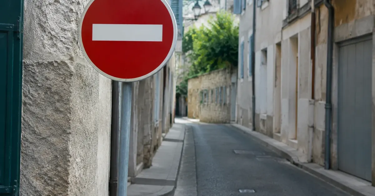 Panneau de signalisation rouge planté devant une rue etroite