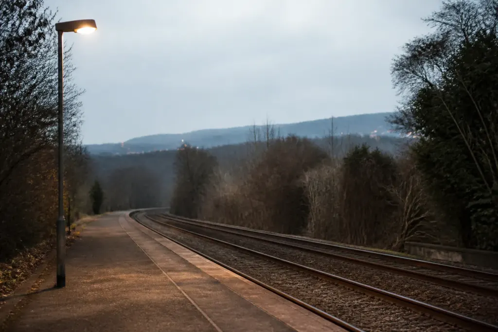 Quai de train desert, lampadaire allume sur trottoir
